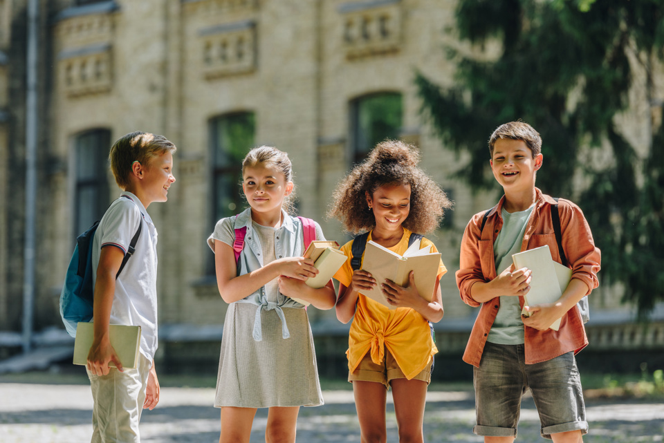 4 young children with backpacks and school books